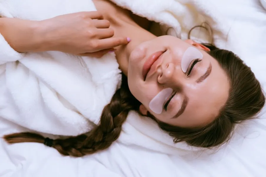 A girl smiling with eye patches under her eyes.